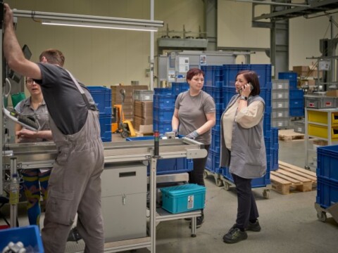 Workers in a factory setting collaborating around machinery.