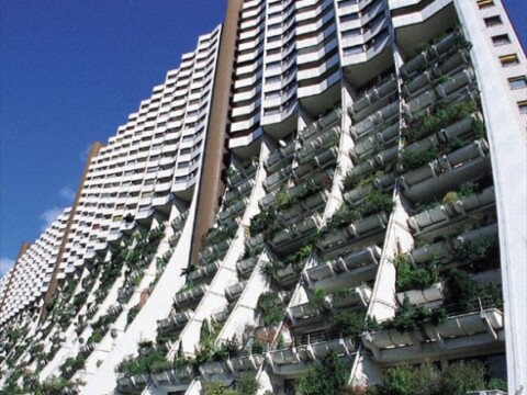 A modern residential building with multiple levels featuring curved balconies and lush greenery.