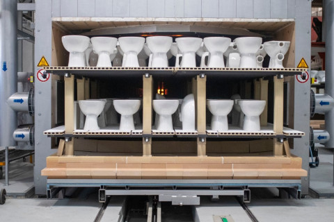 A production line displaying multiple white toilets arranged on shelves inside a factory setting.