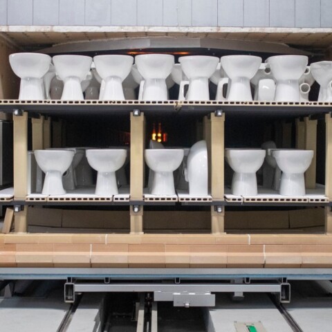 Eine Reihe von Toiletten, die in einer Produktionsanlage zum Brennen aufgereiht sind.