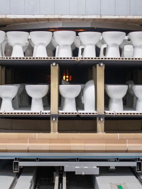 A production line displaying multiple white toilets arranged on shelves inside a factory setting.