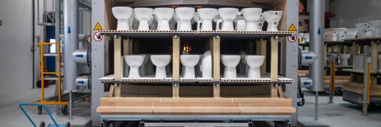 A production line displaying multiple white toilets arranged on shelves inside a factory setting.