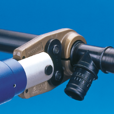 Eine Verbindung von zwei Rohrteilen mit einem speziellen Verbindungselement, beleuchtet vor blauem Hintergrund.