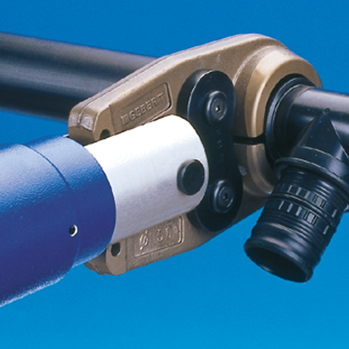 Nahaufnahme einer Rohrverbindung mit einem speziellen Verbindungselement und einem Werkzeug, das die Verbindung herstellt.