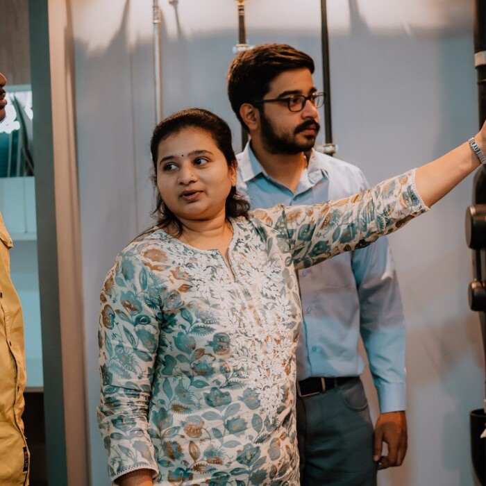 A group of four individuals stands around a display, with one person pointing to a pipe system.