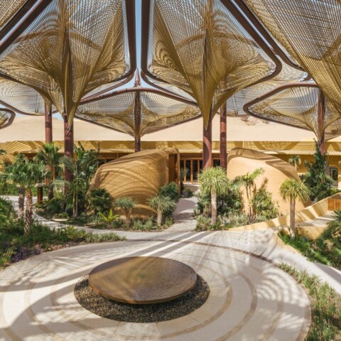 A spacious, modern outdoor area with large, artistic canopy structures and lush greenery surrounding.