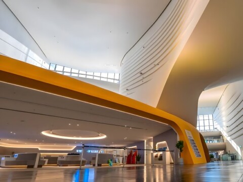 A modern, spacious interior of a building featuring curved architectural lines and bright lighting.