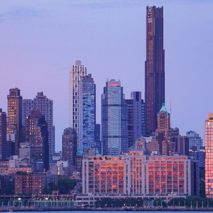 City skyline featuring a mix of modern skyscrapers during a sunset with pastel skies.
