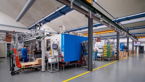 Fabrikationshalle mit Maschinen und einem Arbeiter, der an einem Fertigungsprozess arbeitet.