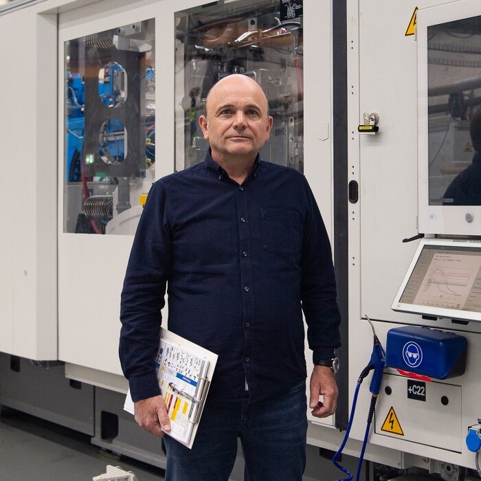 Ein Mann steht in einer Fabrikhalle neben einer grossen, modernen Maschinenanlage.