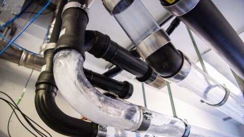 Eine komplexe Anordnung aus schwarzen und transparenten Rohrleitungen, die an einer Decke montiert sind.