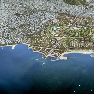 Aerial view of a coastal city with urban areas, green parks, and waterfront along the sea.