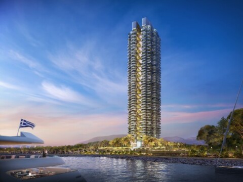 A modern, tall residential tower with a unique design set against a scenic waterfront background and blue sky.