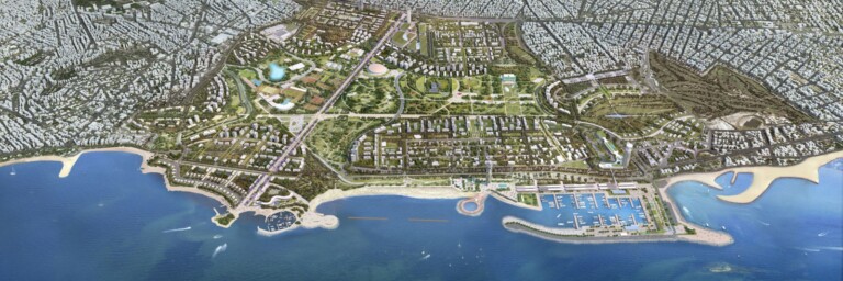 Aerial view of a coastal urban development featuring green spaces, residential areas, and a marina along the shoreline.