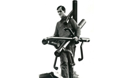 Ein Mann, der verschiedene Rohre in den Händen und um seinen Körper trägt.