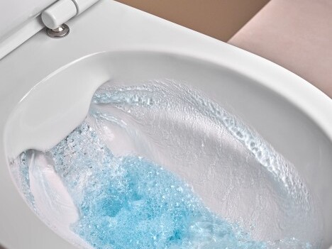 Ein Toilettenbecken mit sprudelndem, blauem Wasser und schäumenden Blasen.