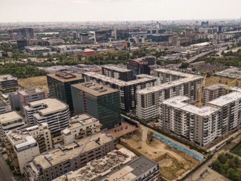 Luftaufnahme einer modernen städtischen Umgebung mit Wohn- und Bürogebäuden, Bauarbeiten und Grünflächen.
