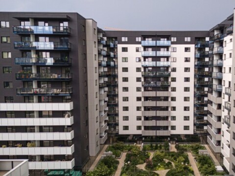 Mehrstöckige Wohngebäude mit Balkonen und einem angelegten Garten im Innenhof.