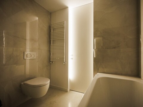 Ein modernes Badezimmer mit hellen, minimalistischen Fliesen und einer wandhängenden Toilette.