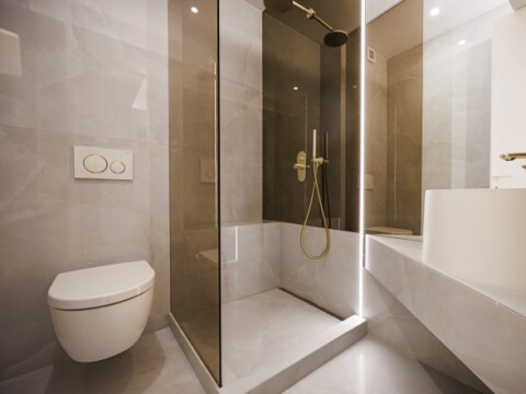 Moderne Badezimmeransicht mit Dusche, WC und minimalistischem Design in neutralen Farben.