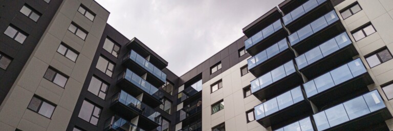 Moderne Wohnanlage mit mehreren Etagen und Balkonen, grauer Himmel im Hintergrund.