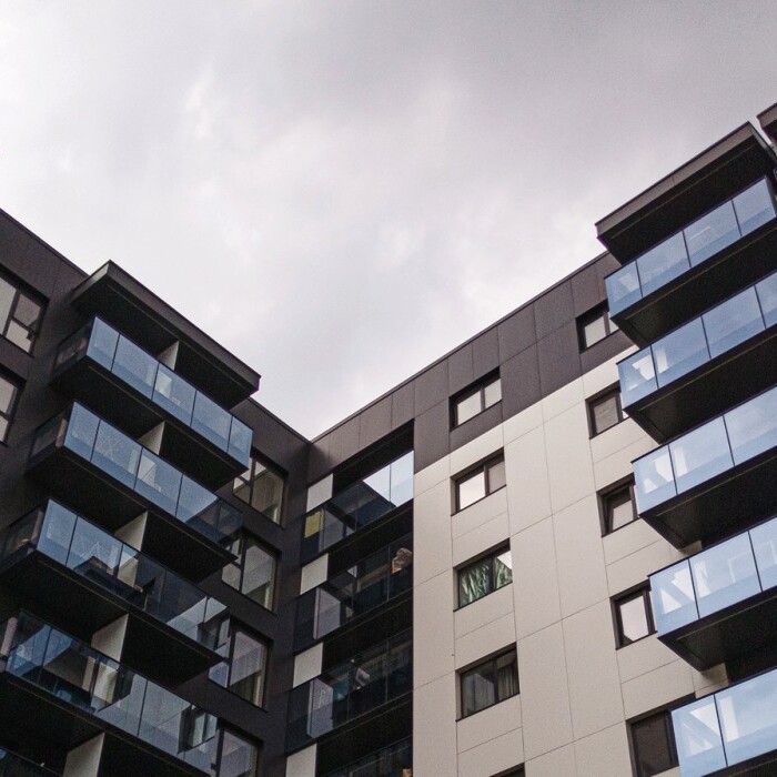 Moderne Wohnanlage mit mehreren Etagen und Balkonen, grauer Himmel im Hintergrund.