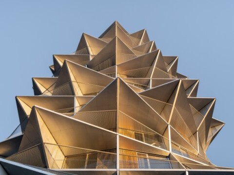 Eine auffällige, spitze Gebäudestruktur mit spitzen, dreieckigen Facetten und Balkonen, die in den Himmel ragt.