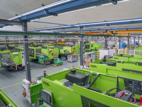 A spacious manufacturing facility filled with multiple green industrial machines, showcasing a modern production environment.