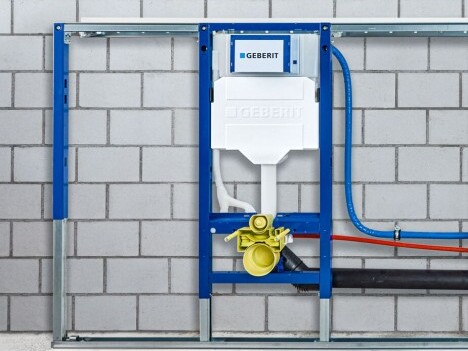 Wandmontiertes Geberit-Installationssystem mit blauem Gestell und Rohren in einem Mauerwerk.