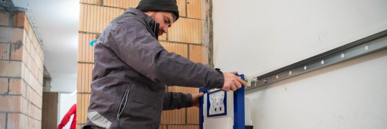 Ein Handwerker montiert einen Duofix an einer Wand in einem Rohbau.
