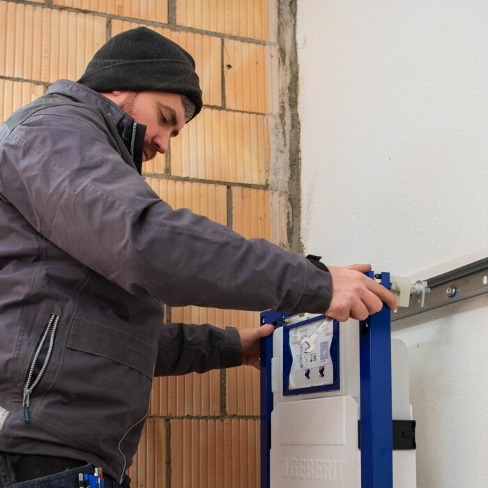 Ein Handwerker montiert einen Duofix an einer Wand in einem Rohbau.