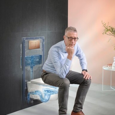 A man sitting on a modern toilet while an abstract water flow graphic is visible.