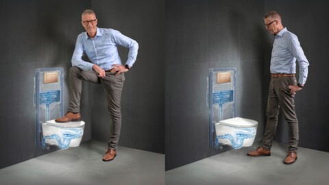 A man poses beside a wall-mounted toilet showcasing its installation against a dark wall.