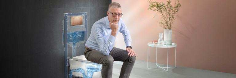 A man sitting on a modern toilet with a stylized transparent depiction of the toilet's internal mechanism in the background.