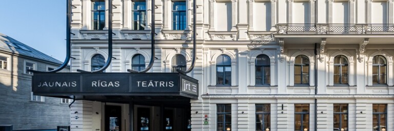 Theater building with a prominent black entrance sign reading "Jaunais Rīgas Teātris."