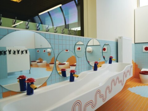 A colorful, modern bathroom with curved sinks, circular mirrors, and playful tile patterns.