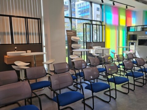 A waiting area featuring rows of modern blue and gray chairs and colorful vertical blinds.