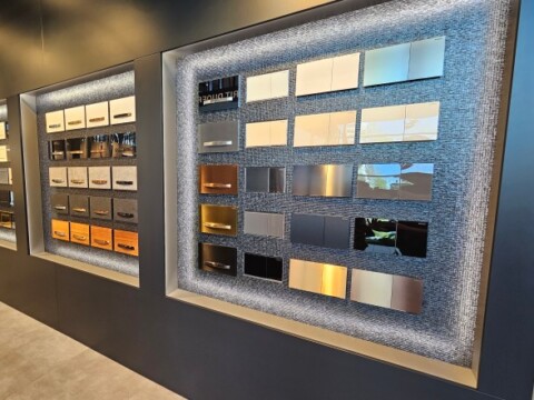 Display of various actuator plate samples arranged on a wall, showcasing textures and colours.