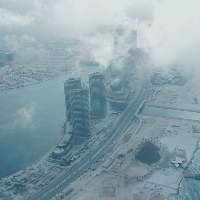 Städtische Küstenansicht mit hochmodernen Gebäuden, umgeben von Wasser und Nebel.
