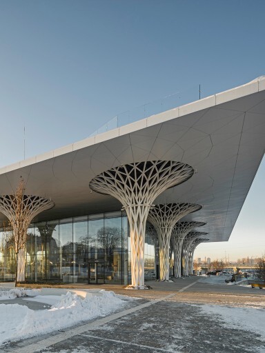 Modernes Gebäude mit einem grossen Dach und stilisierten Säulen, umgeben von Schnee und klarem Himmel.