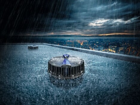 Ein Hochhausdach mit Dachentwässerung, umgeben von starkem Regen und dunklen Wolken, mit einer Stadtansicht im Hintergrund.