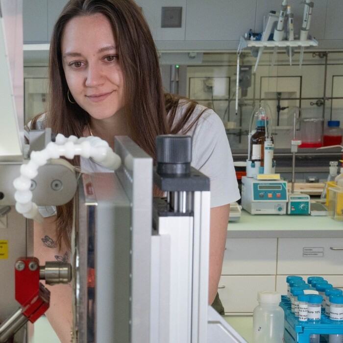 A laboratory setting featuring a woman interacting with a scientific instrument, surrounded by various lab equipment and supplies.