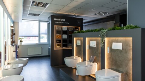 A modern bathroom showroom featuring multiple white toilet installations, sleek lighting, and a display wall showcasing different bathroom fixtures.