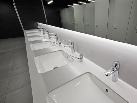 Ein modernes öffentliche Badezimmer mit mehreren Waschbecken und Spiegeln, hell beleuchtet.