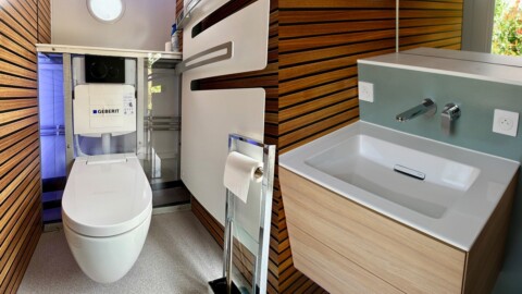 Modern Badezimmer mit Holzverkleidung, einem modernen WC und einem schlichten Waschbecken.