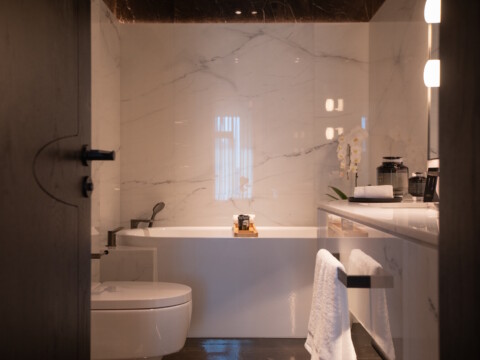 Ein modernes Badezimmer mit Badewanne, Waschbecken, und einer minimalistischen Einrichtung, Blick durch eine offene Tür.