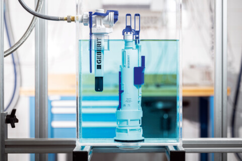 Eine transparente Box mit einer Pumpe im Wasser, umgeben von Laborausrüstung und Workshop-Elementen.