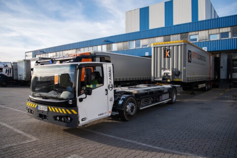 A white industrial truck with yellow and black stripes parked near a loading dock.
