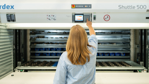Eine Person mit langen, blonden Haaren bedient eine Maschine.