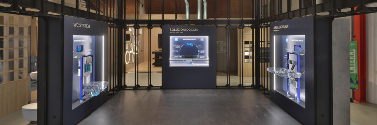 A modern exhibition space with glass and metal structures showcasing high-tech displays and informational panels.